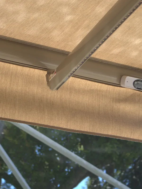 Underside of an extended awning, arm and fabric in daylight