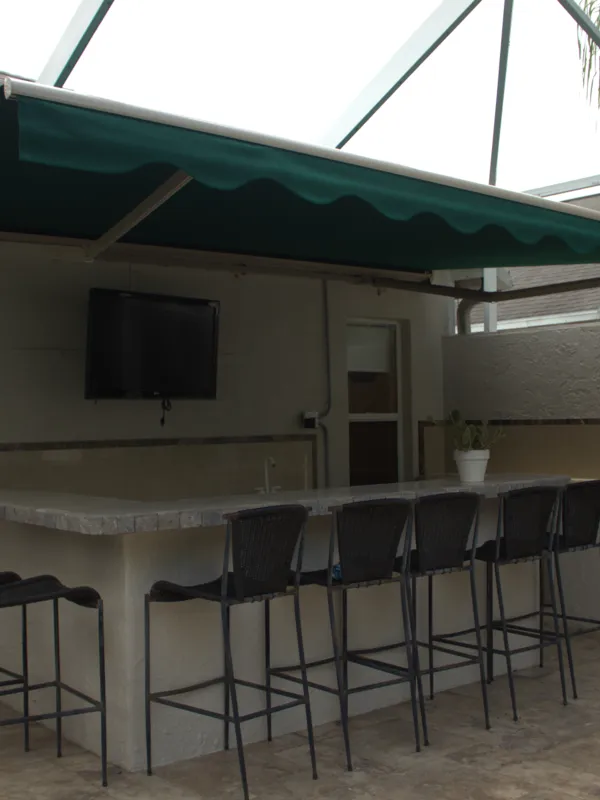 Deep green Sunbrella awning with a scalloped valance over an outdoor bar