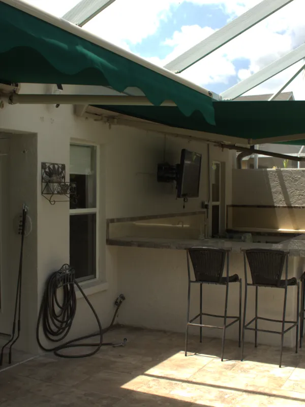 Awning extended over a patio inside a screened cage