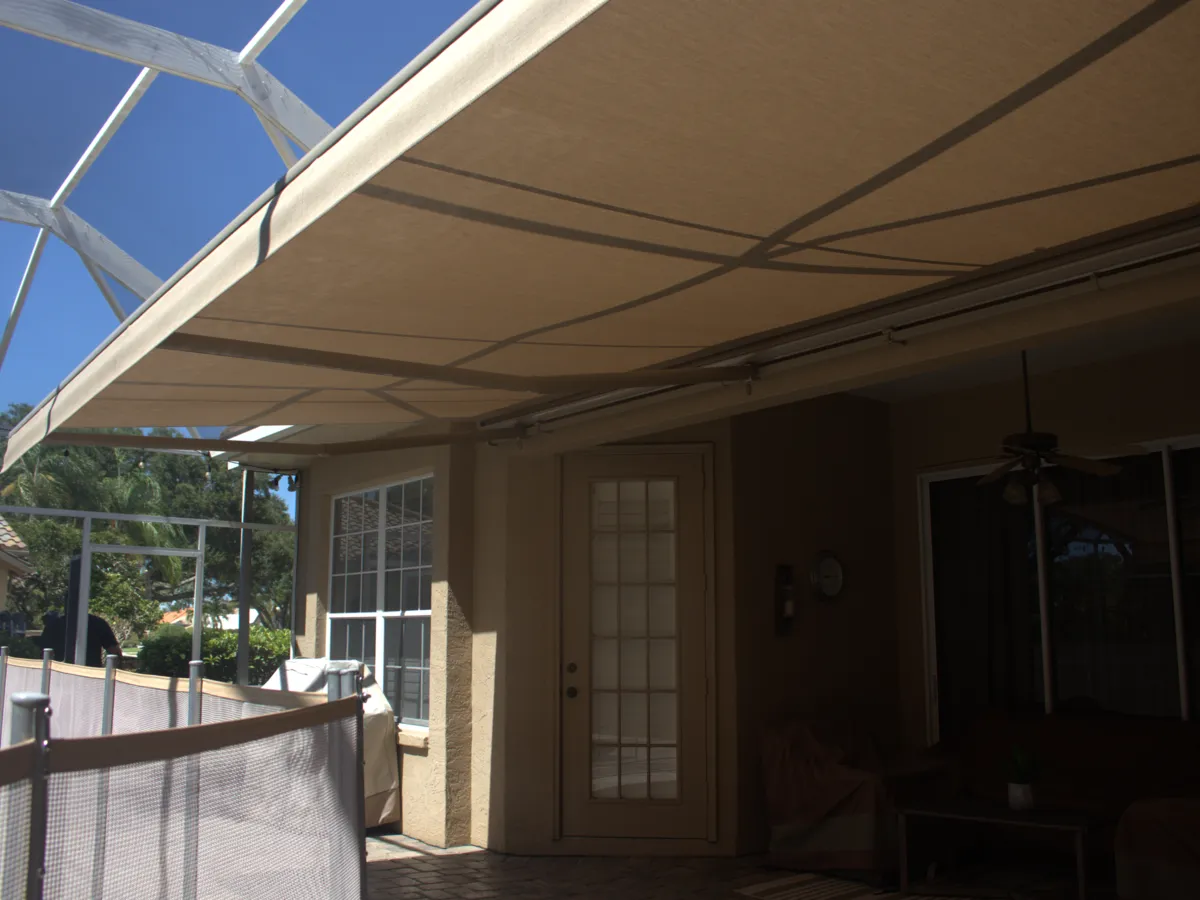 Cream retractable awning extended over a screened patio