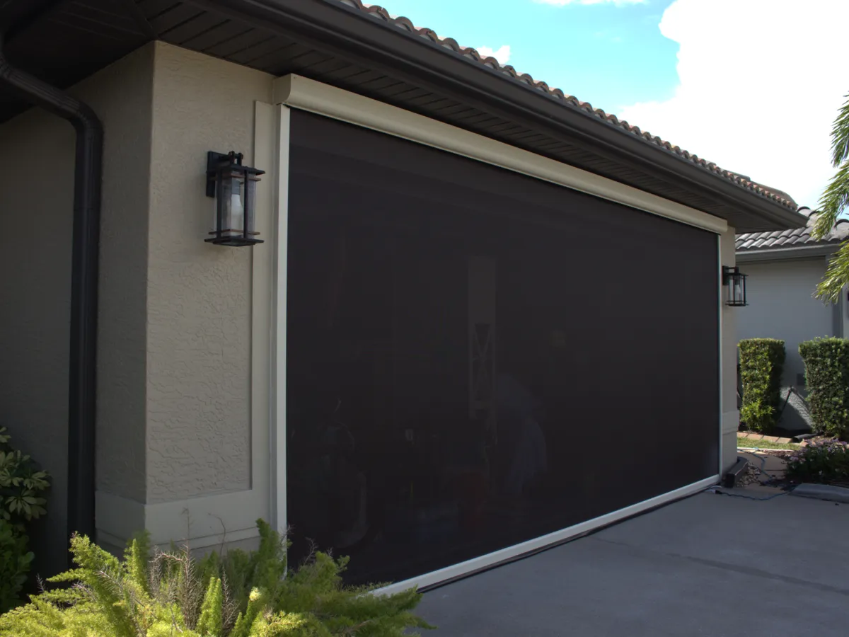 Motorized screen lowered across a two-car garage opening
