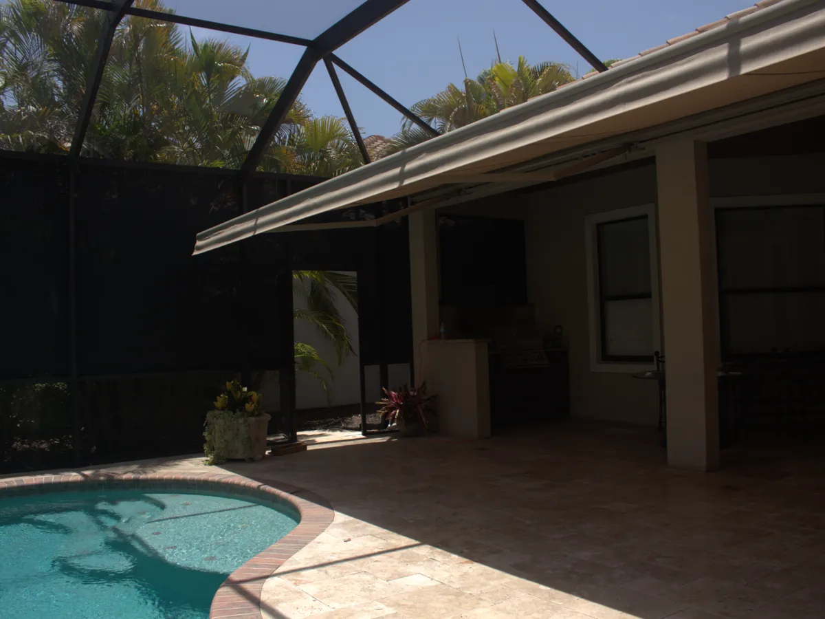Awning extended over a pool deck inside a screened enclosure